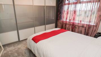 Une chambre à coucher avec un lit, une porte coulissante et une fenêtre avec des rideaux.