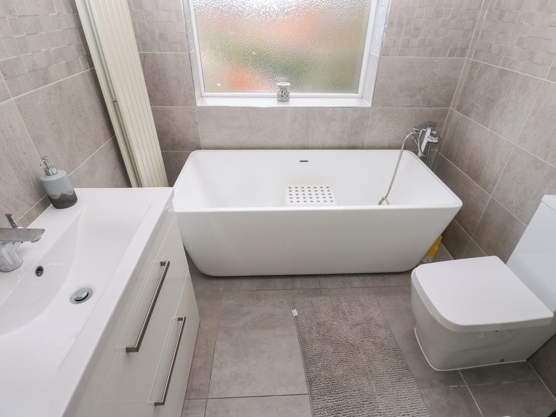 A modern bathroom with a freestanding bathtub, a toilet, and a sink.
