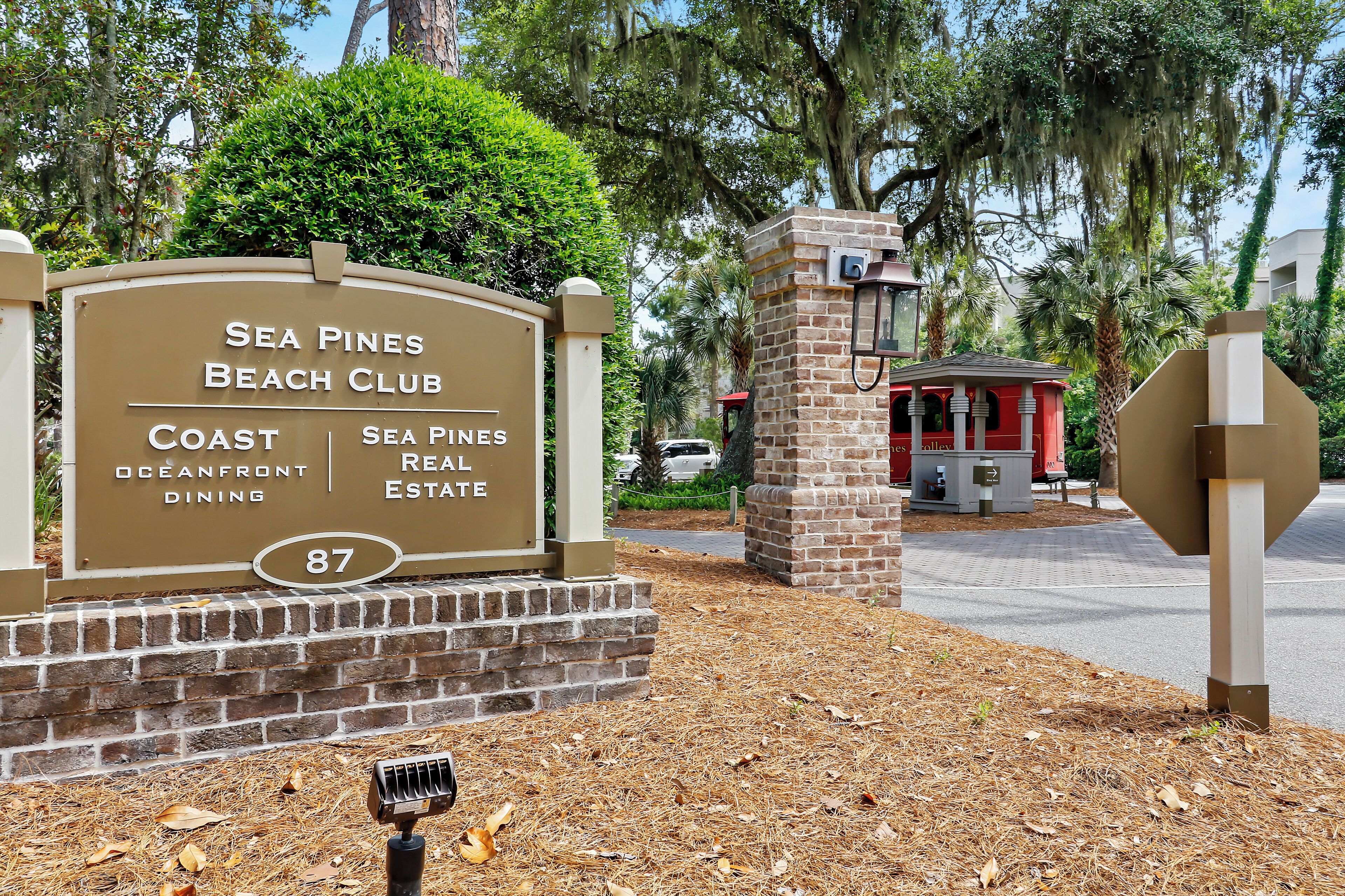 A sign for Sea Pines Beach Club with sections for Coast Oceanfront Dining and Sea Pines Real Estate.