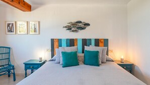 Ein Schlafzimmer mit einem Bett, zwei Nachttischen, einem Sessel und Wandbildern.