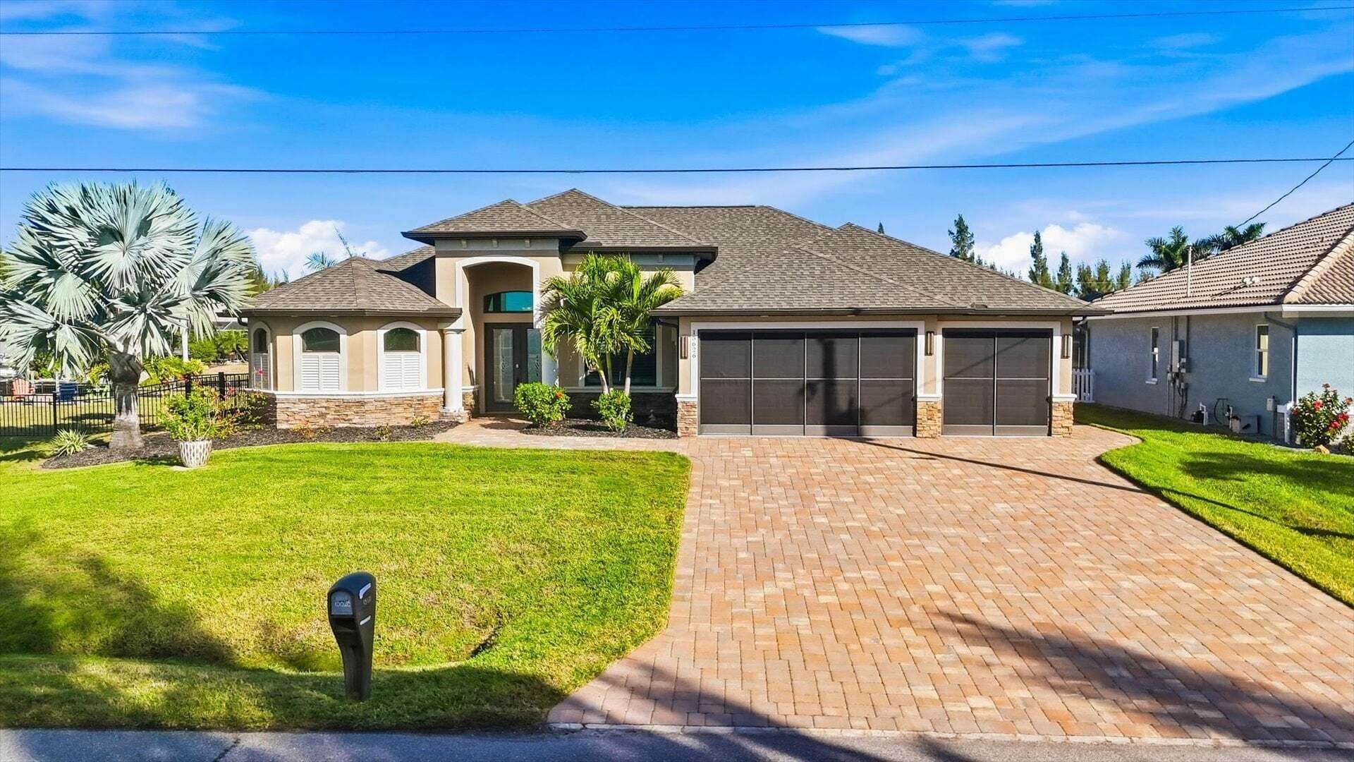 Une maison à deux étages avec un garage, une allée couverte et une pelouse bien entretenue.