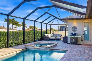 A pool area with a glass enclosure, outdoor seating, and a barbecue grill. - Aqc15626 3 Bedroom Home (Port Charlotte)