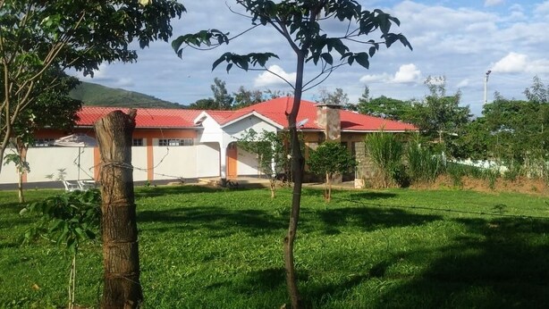 A residential area with houses having red roofs and a grassy lawn. - NevaLand County Hotel (Matiliku)