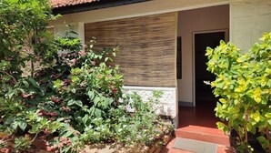 A house with a tiled roof, a stone wall, and a wooden door. - NevaLand County Hotel (Matiliku)