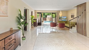 A spacious hallway with a large potted plant, a wooden cabinet, and a patterned rug. - Villa The Hidden Palm, Piscadera, Private Pool (Willemstad)