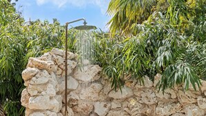 A stone wall with a showerhead, surrounded by lush greenery. - Villa The Hidden Palm, Piscadera, Private Pool (Willemstad)