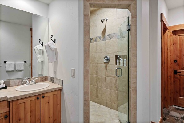 A modern bathroom with a wooden vanity, a glass-enclosed shower, and a large mirror. - 5br Retreat W/ Hot Tub At Deer Valley Base 5 Bedroom Condo (Park City)