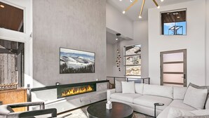 A modern living room with a fireplace, a large sofa, and a coffee table. - Luxury 4br W/ Hot Tub & Deer Valley Access 4 Bedroom Home (Heber City)