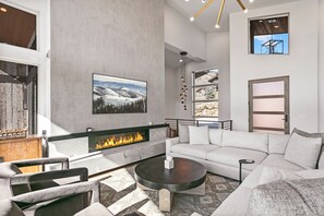 A modern living room with a fireplace, a large sofa, and a coffee table. - Luxury 4br W/ Hot Tub & Deer Valley Access 4 Bedroom Home (Heber City)
