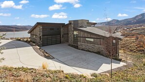 A modern house with a garage, a driveway, and a view of mountains and a lake. - Luxury 4br W/ Hot Tub & Deer Valley Access 4 Bedroom Home (Heber City)