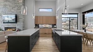 Une cuisine moderne dotée d’un grand îlot central, de meubles en bois et d’une cheminée en pierre.