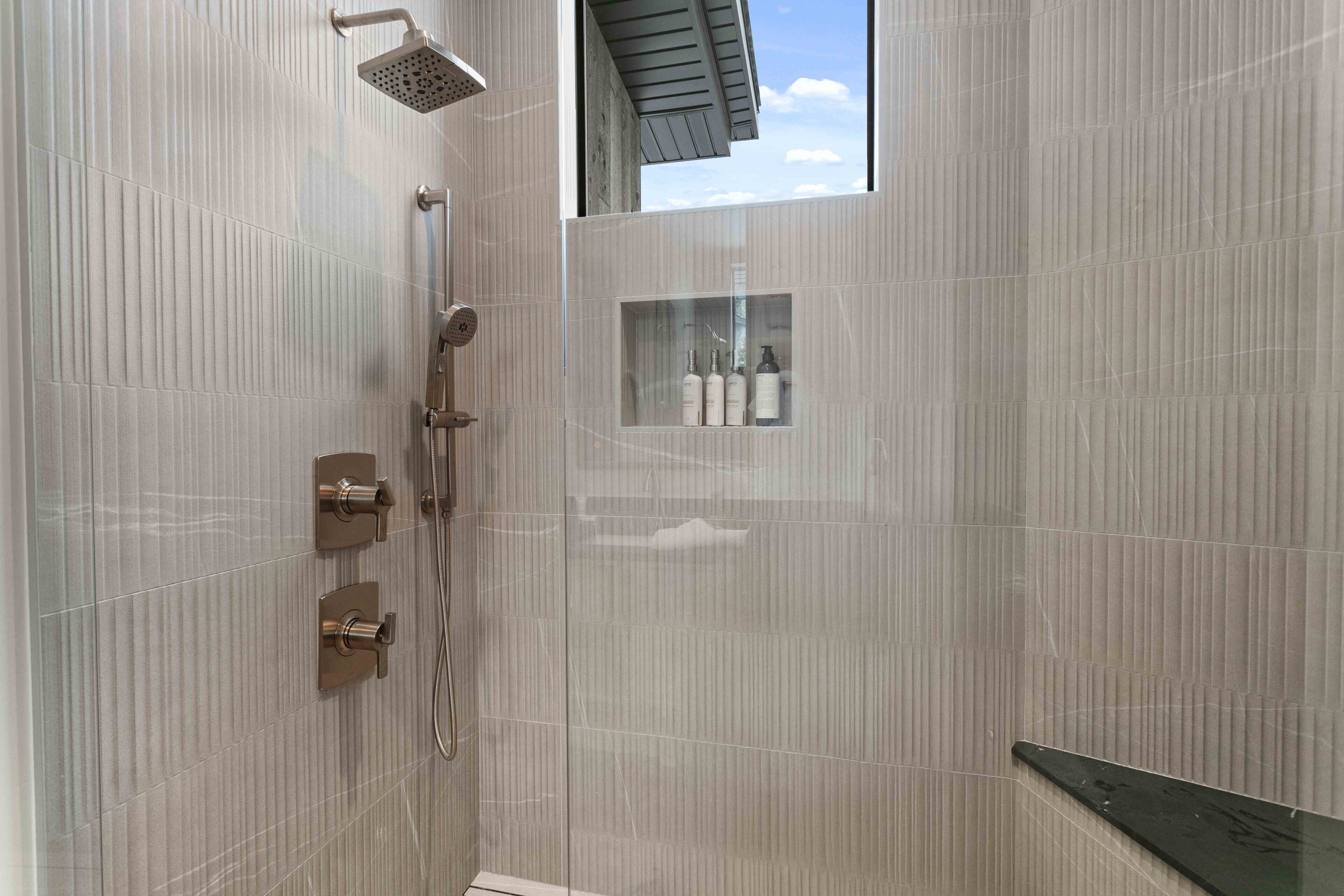 Una ducha moderna con cabina de vidrio, cabezal de ducha tipo lluvia y panel de control.