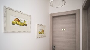 A hallway with two framed fruit paintings on the wall, a wooden door with a number plate, and a light fixture above. - Fiordarancio is the guest house you were looking for, located in a fantastic position right above the beaches of Fegina. The room offers you a sea view balcony, double bed, private bathroom and air conditioning.PLEASE remember that in order to find yours (Monterosso)