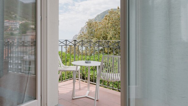 A balcony with white chairs and a table, overlooking a mountainous landscape. - Fiordarancio is the guest house you were looking for, located in a fantastic position right above the beaches of Fegina. The room offers you a sea view balcony, double bed, private bathroom and air conditioning.PLEASE remember that in order to find yours (Monterosso)