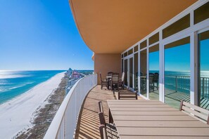 Un balcón con vistas a la playa y al océano, amueblado con sillas y una mesa.
