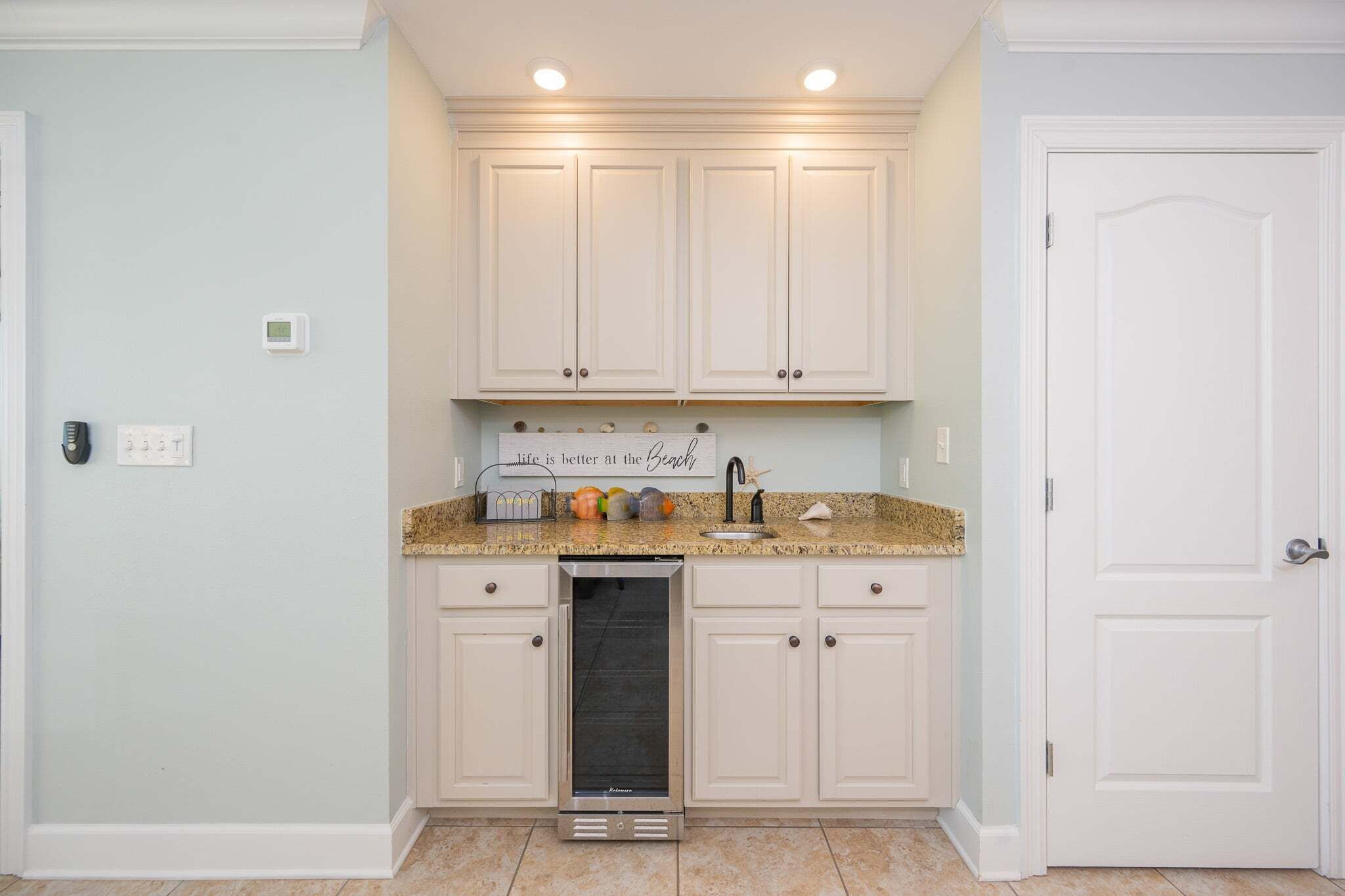 A kitchen with white cabinets, a granite countertop, and a built-in dishwasher.