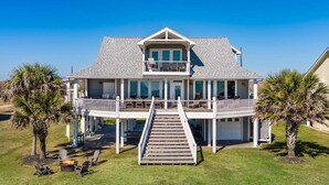A two-story house with a balcony, a covered deck, and a staircase leading to the deck. - Seagrape 5 Bedroom Home (Port Bolivar)