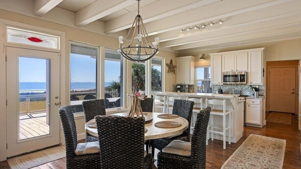 A spacious kitchen with white cabinets, a central island, and a view to the outside. - Seagrape 5 Bedroom Home (Port Bolivar)