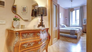 Un dormitorio con un aparador de madera, una cama, un espejo y una ventana con cortinas.