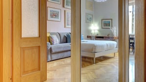 Un dormitorio con cama, sofá y escritorio. Hay cuadros en la pared.