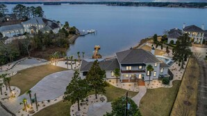 Une grande maison moderne dotée d’un vaste patio et offrant une vue sur un lac paisible.