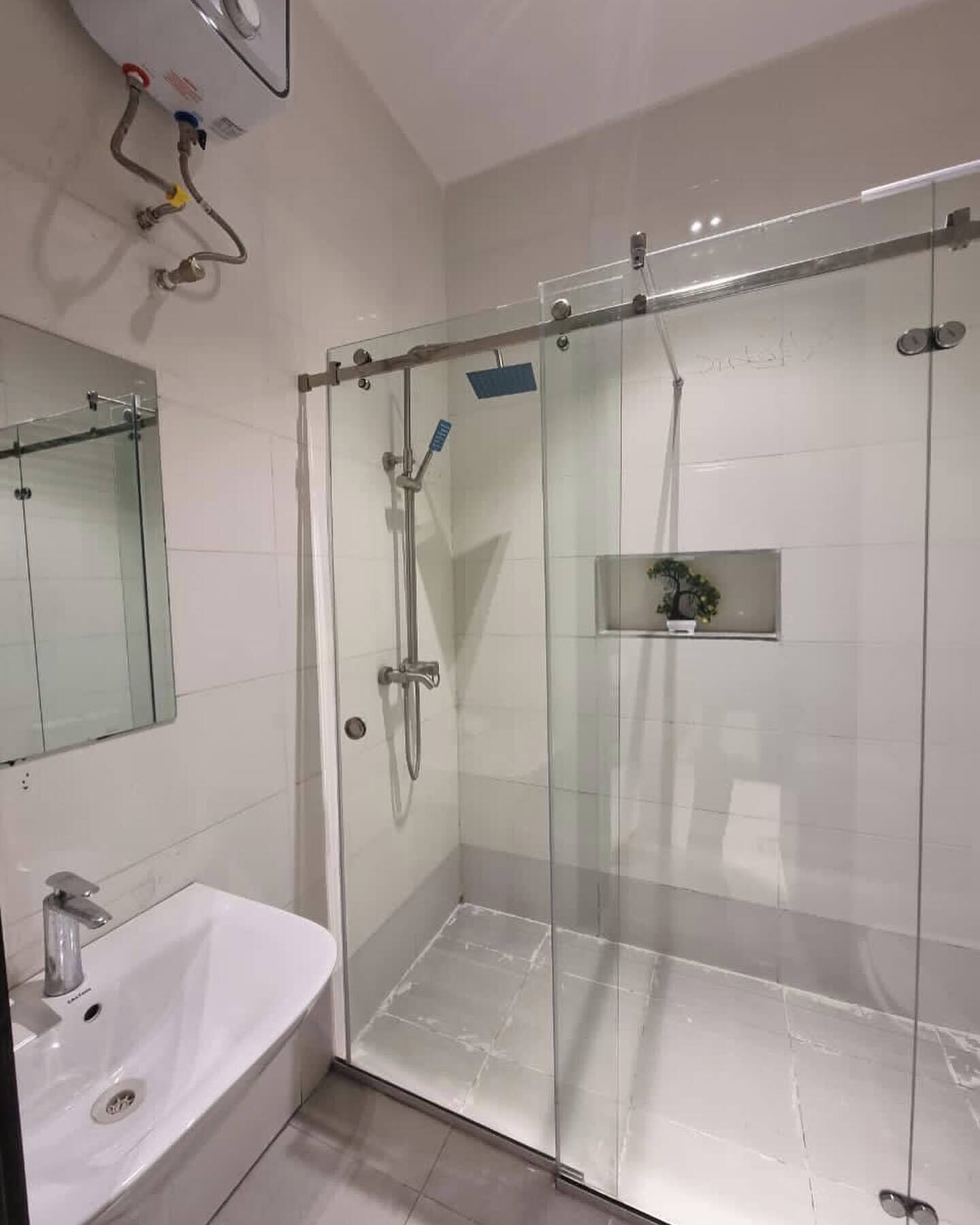 Une salle de bain moderne avec une douche à parois de verre, un lavabo blanc et un miroir au-dessus du lavabo.