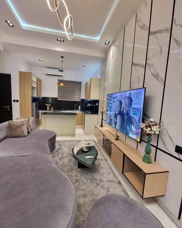 A modern living room with a grey sofa, a coffee table, and a TV on a wooden stand.