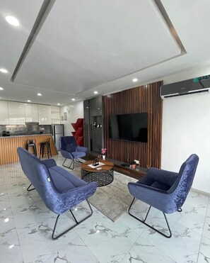 A modern living area with a kitchen, a flat-screen TV, and a seating arrangement. - Cherry Home Solutions (Lekki)