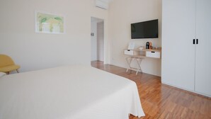 Ein Schlafzimmer mit Bett, Schreibtisch, Stuhl, Fernseher und Kleiderschrank.
