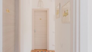 Ein Korridor mit einer Holztür, einer Lampe und gerahmten Kunstwerken an der Wand.