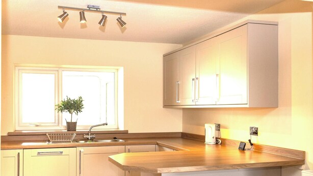 Een moderne keuken met een houten aanrecht, een inbouwspoelbak en een raam met een plant.