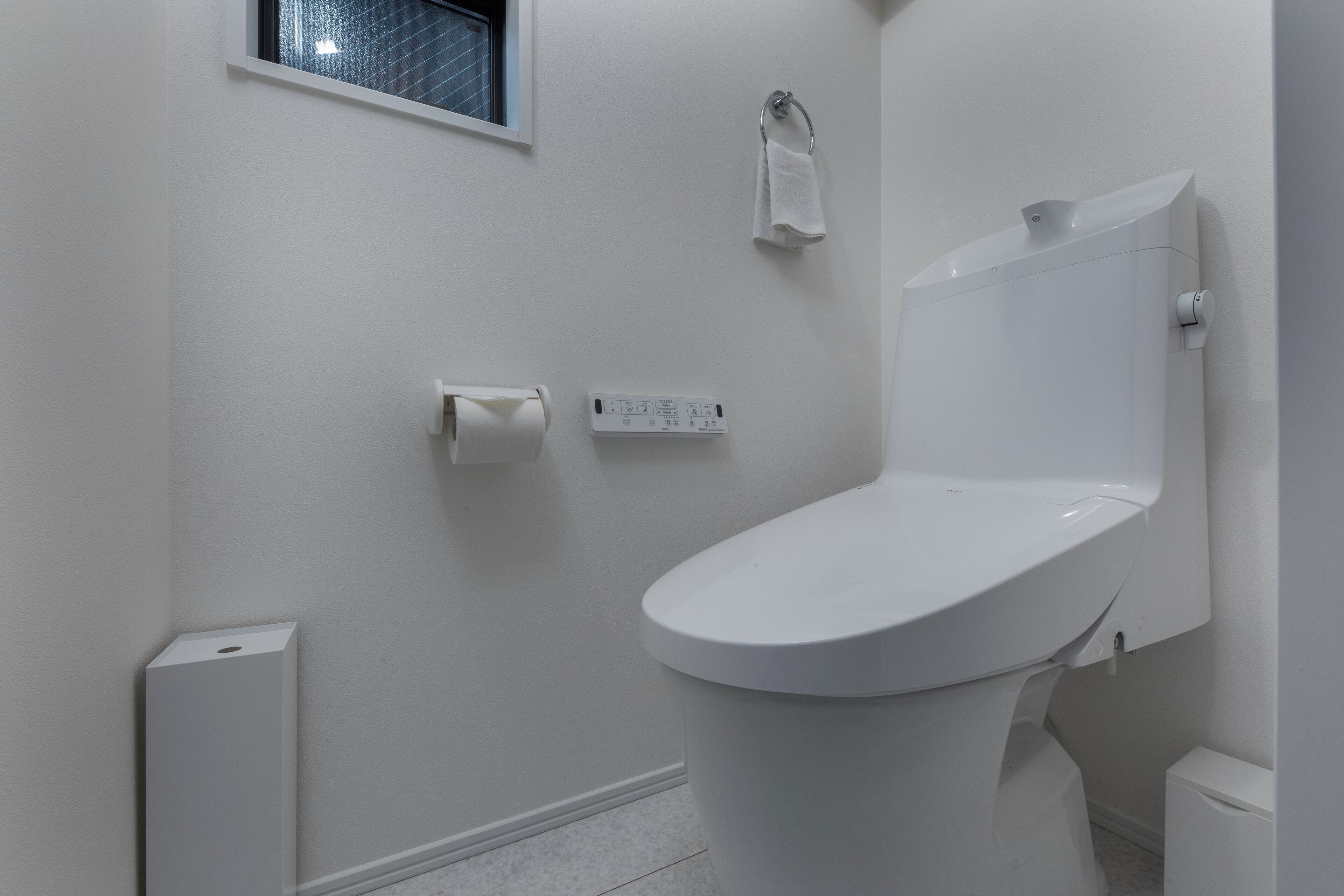A modern bathroom with a toilet, a towel rack, and a window.