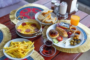 Una mesa servida con alimentos para el desayuno, como pan, huevos y un vaso de jugo de naranja.