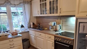 Une cuisine avec des armoires blanches, un évier, une cuisinière et un réfrigérateur.