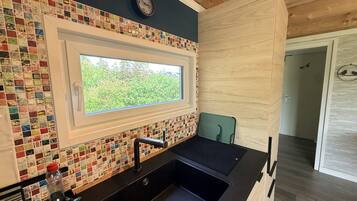 Eine moderne Küche mit farbenfroher Mosaik-Spritzschutz, einem Fenster und einem Spülbecken.