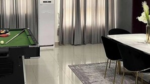 A modern dining area with a pool table, a dining table with chairs, and a pendant light.