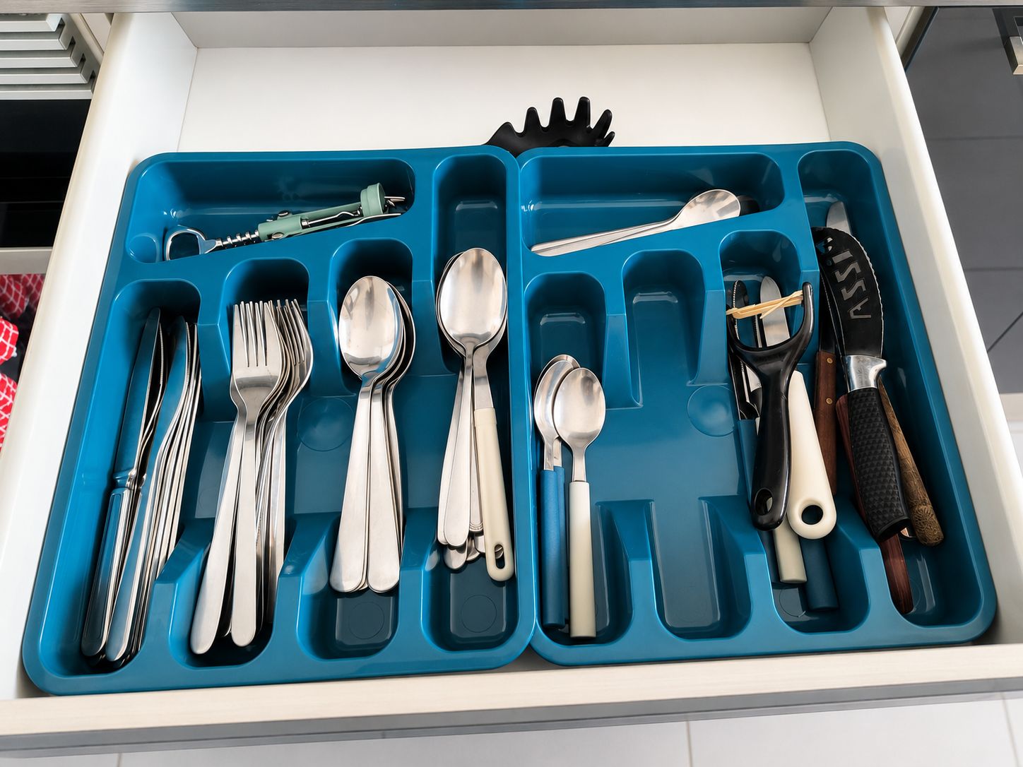 A drawer with compartments containing various kitchen utensils and tools.
