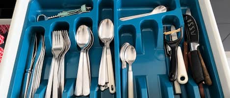 A drawer with compartments containing various kitchen utensils and tools.