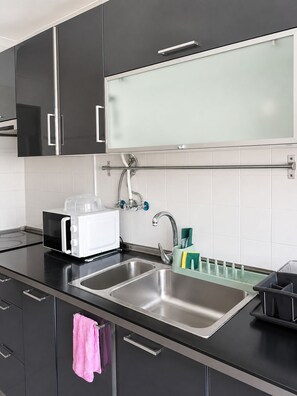 Eine moderne Küche mit integriertem Mikrowellenherd, Spülbecken aus Edelstahl und einer Glasrückwand.