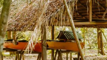 A rustic wooden structure with a thatched roof, a table, and a bench.