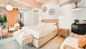 Un dormitorio moderno con una cama grande, vigas de madera en el techo, un armario de madera, un escritorio y una silla.