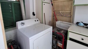 Un lavadero pequeño con lavadora, tendedero y un mueble.