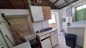 Una cocina compacta con servicios básicos, que incluye lavadora, un lavamanos pequeño y un armario de almacenamiento.