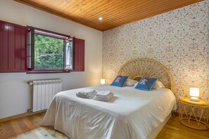 Ein Schlafzimmer mit einem Bett, einem Fenster, einer Heizung und einer Wand mit Blumenmuster.