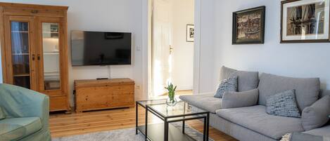 A living room with a sofa, a glass coffee table, a wooden cabinet, and a television.