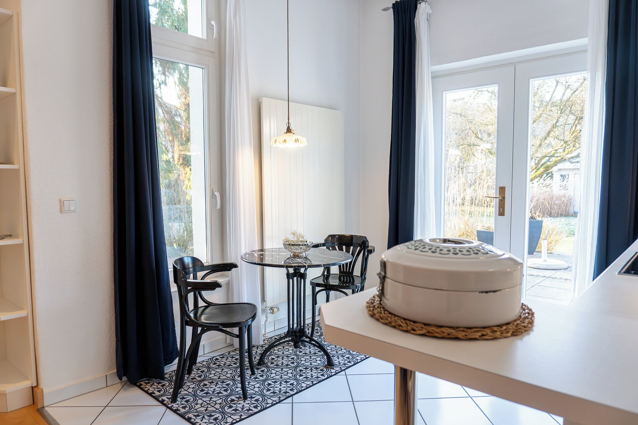 Ein Essbereich mit einem runden Tisch, schwarzen Stühlen, einer weißen Tischdecke und einer Torte auf dem Tisch.