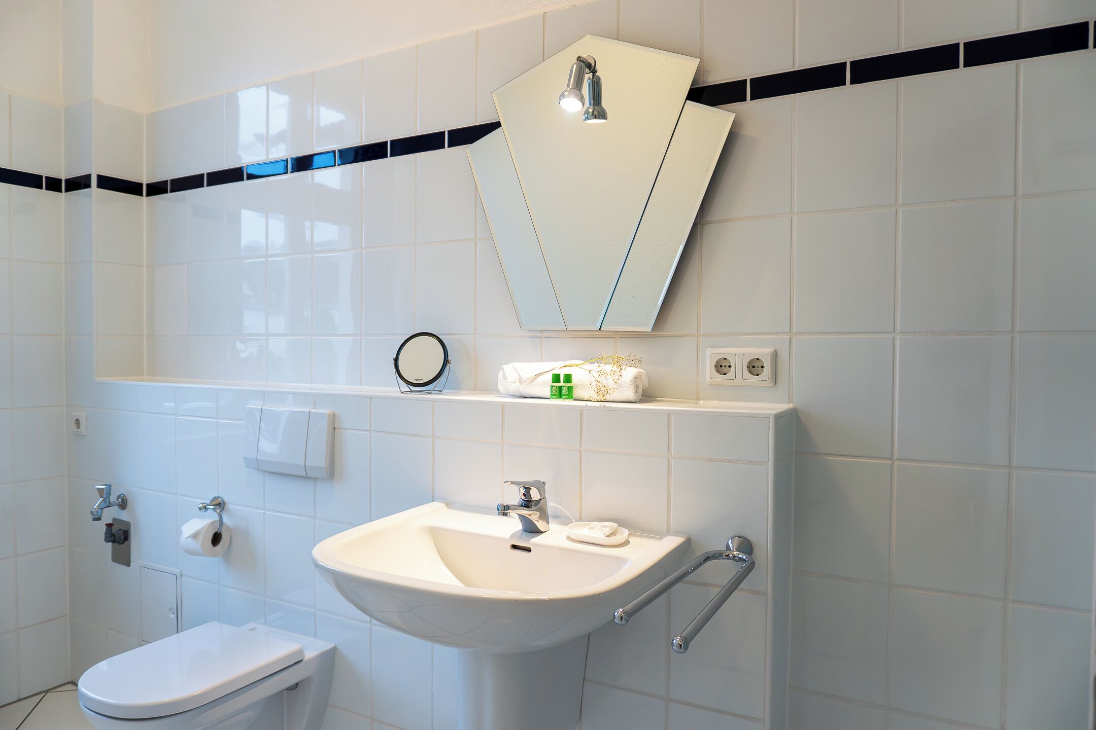 A bathroom with a white sink, mirror, and toilet.