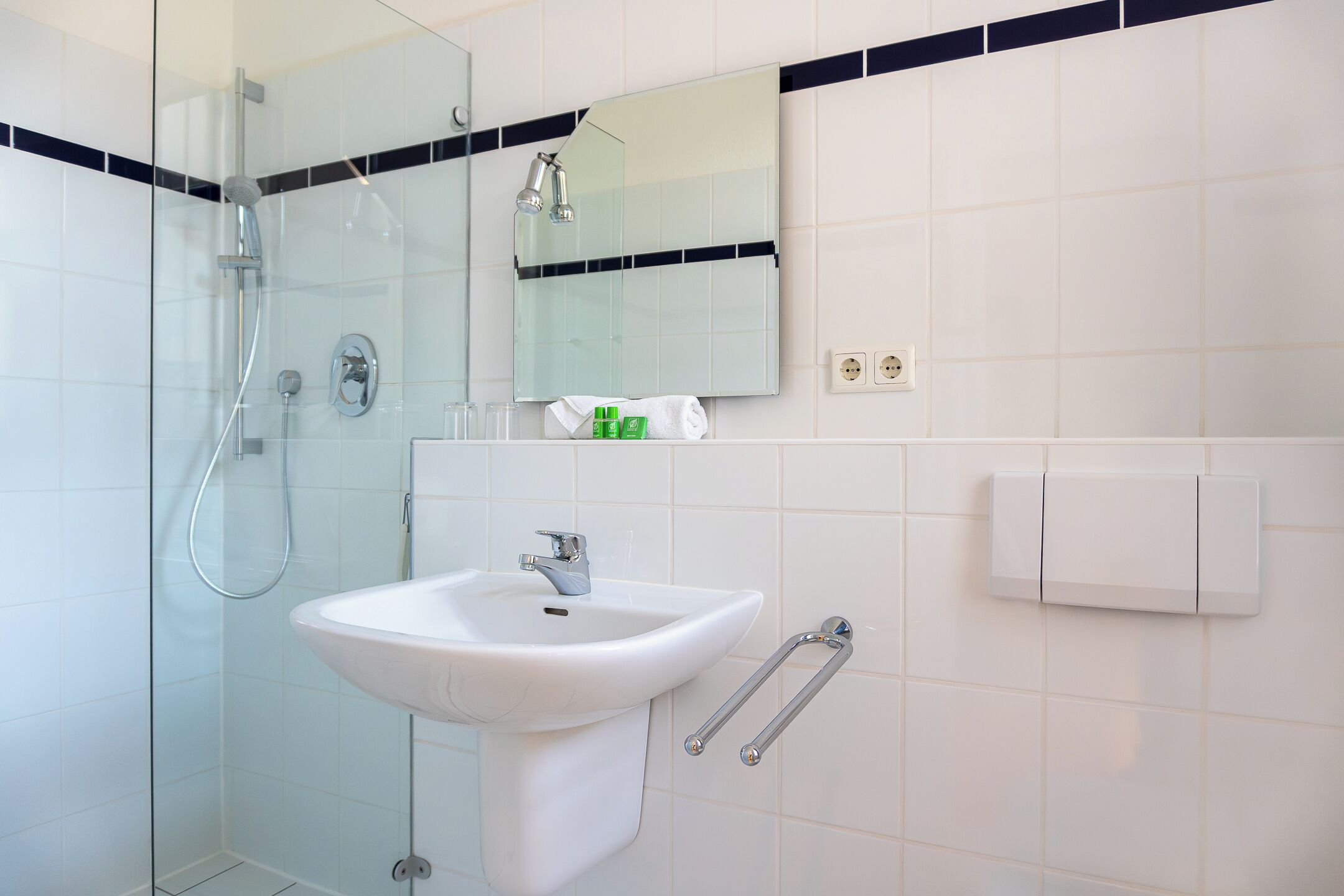 A modern bathroom with a glass-enclosed shower, a white sink, and a mirror above it.
