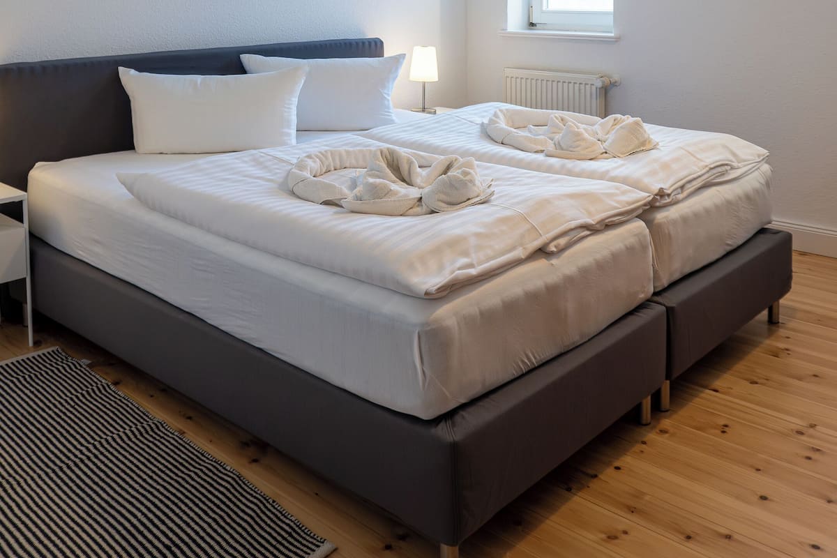 A modern bedroom with a large bed, a bedside table, a lamp, and a window.