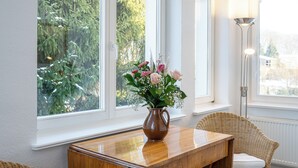 A dining area with a wooden table, wicker chairs, and a vase of flowers. - Villa Cremona (Seebad Bansin)